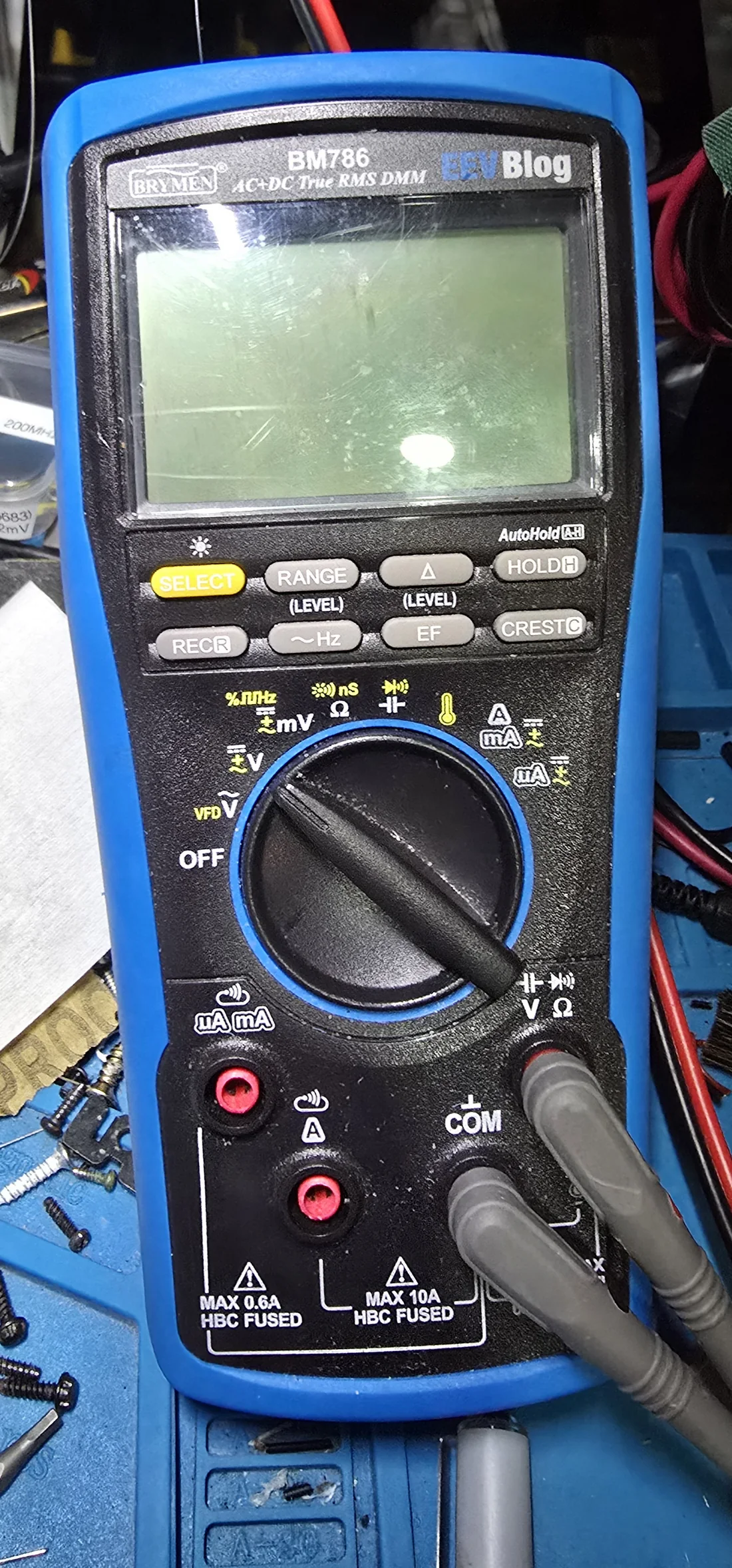 A Brymen digital multimeter with test leads attached, resting on a workbench.