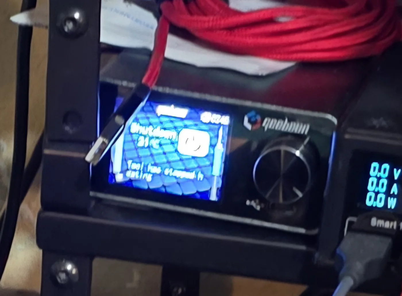 The Geeboon soldering station powered on, showing its colour display and control knob.