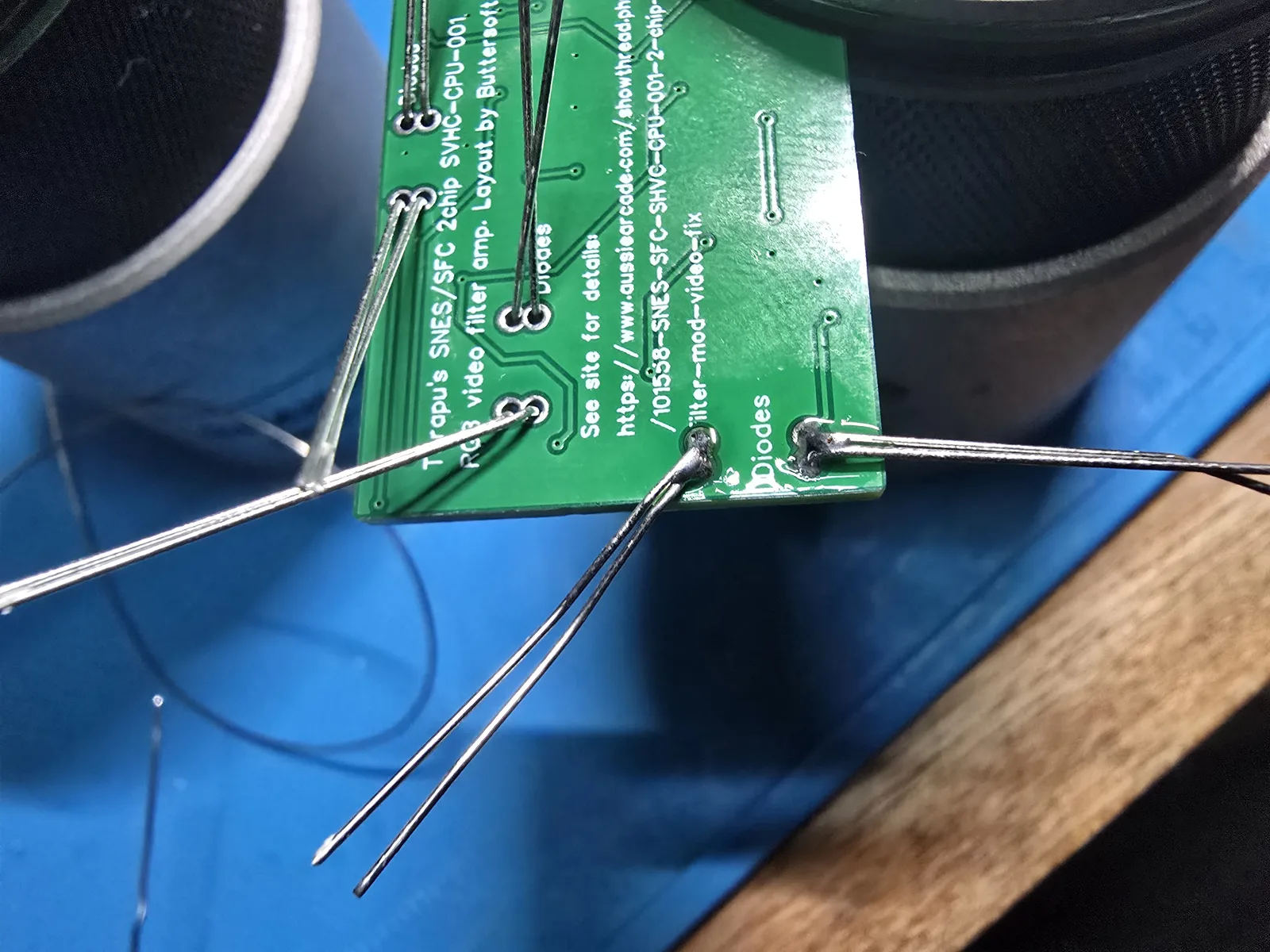 The underside of the mod board showing diode leads bent flat against the board to hold the parts in place before soldering.