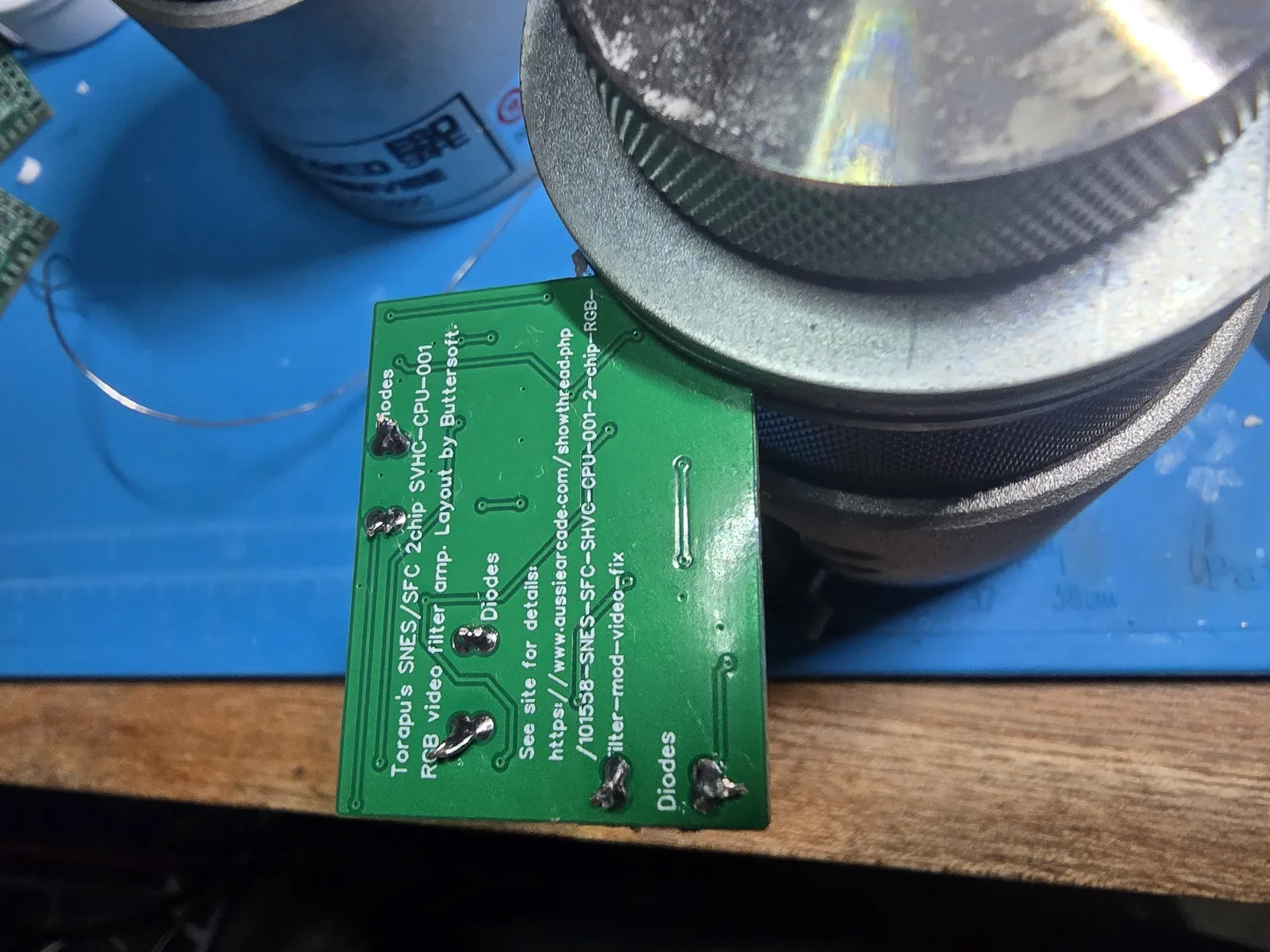 The underside of the mod board after the diode leads have been soldered and clipped, with solder joining the pads of each pair.