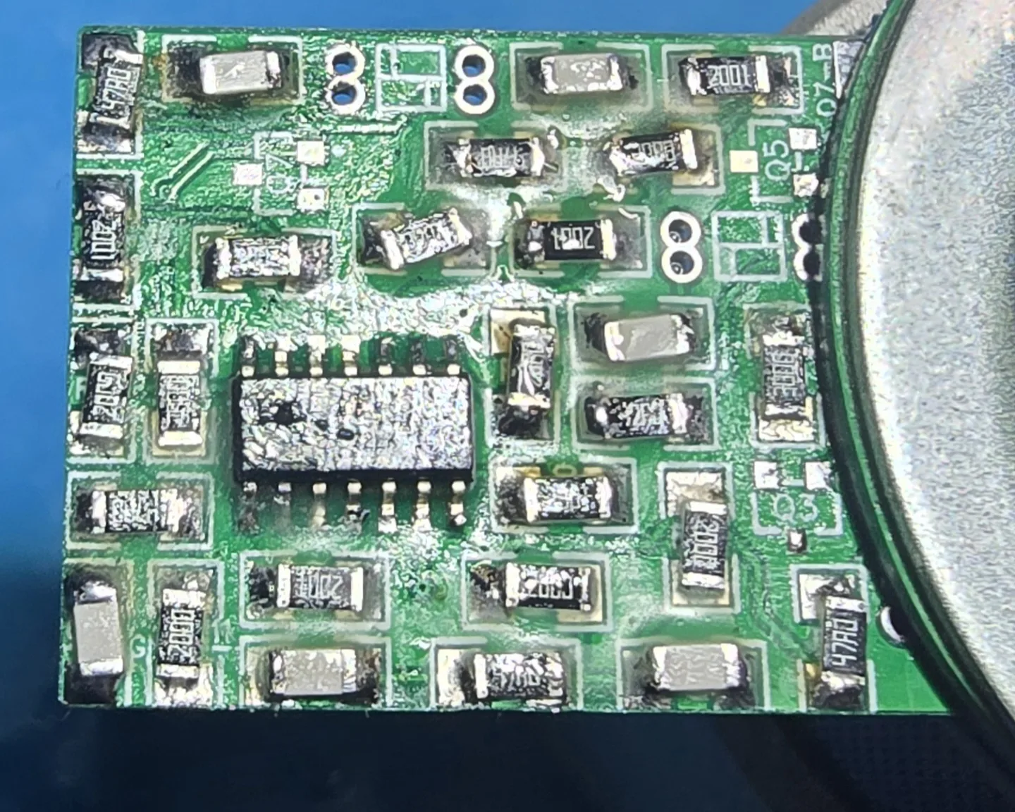Close-up of the populated mod board straight off the soldering iron. The surface-mount resistors sit at visibly different angles on their pads, several rotated a few degrees out of square with the white silkscreen outlines around them.