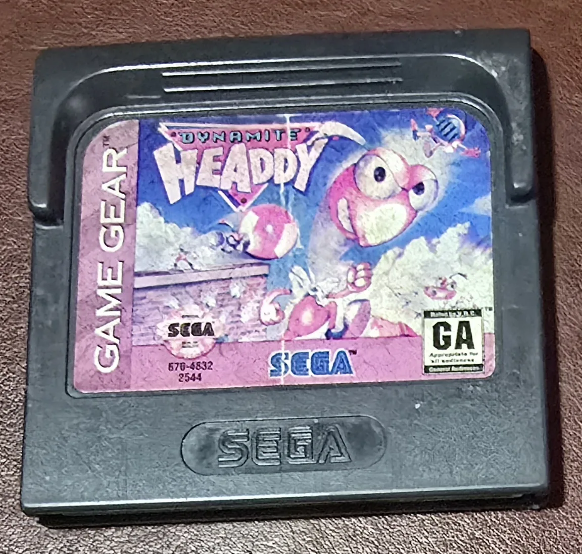 Front of an authentic Sega Game Gear Dynamite Headdy cartridge, the pink Headdy character on a purple label