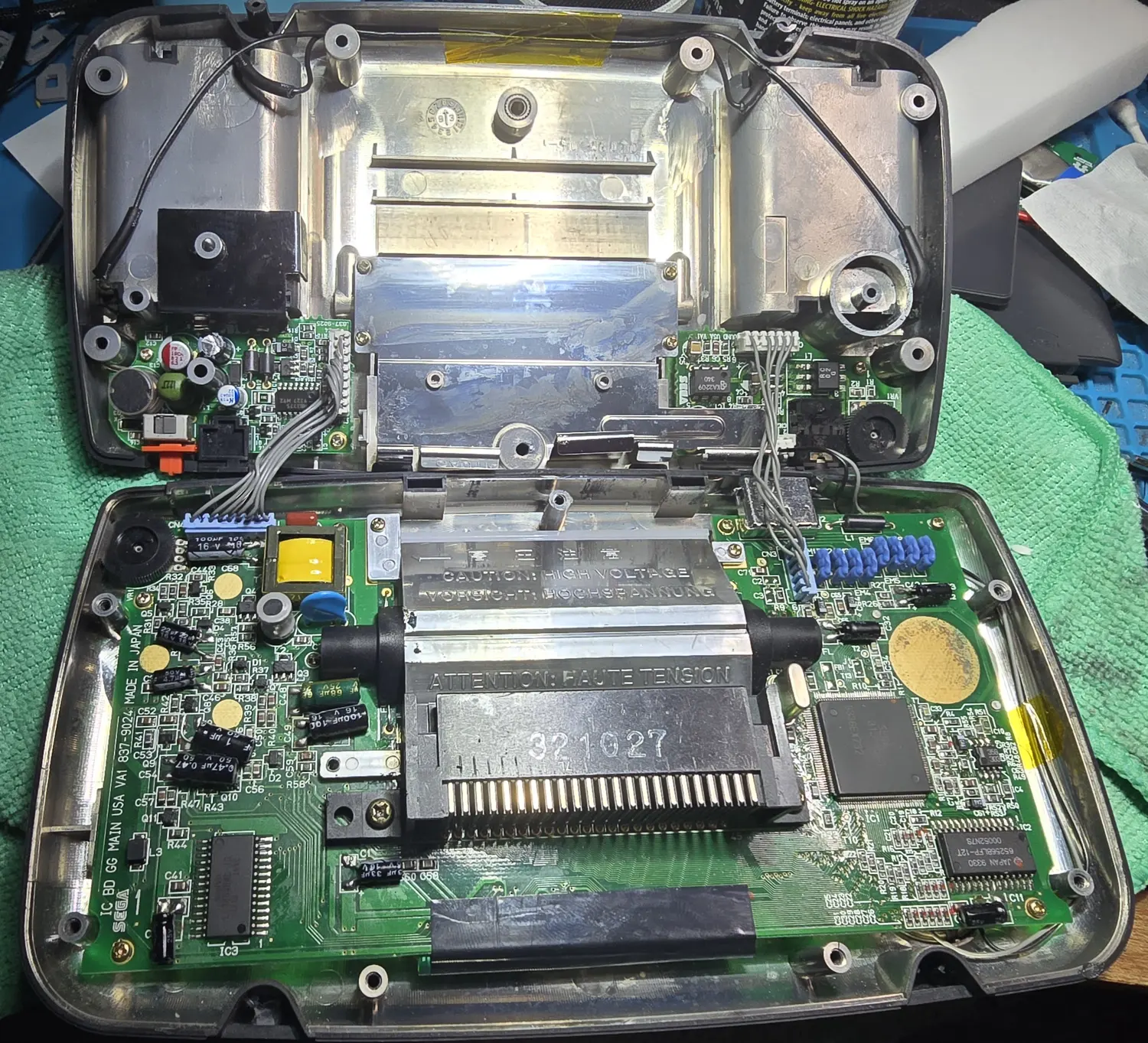 The Game Gear opened on the bench after the recap, both shell halves apart, showing all three boards