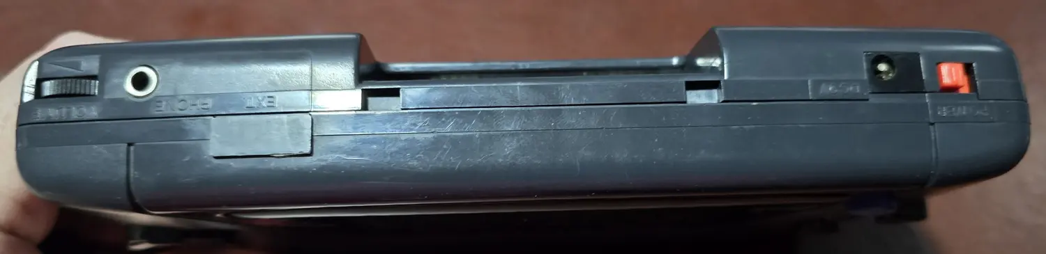 Top edge of the Game Gear showing the volume wheel, headphone jack, EXT port with its cover still fitted, cartridge slot, DC jack and power switch