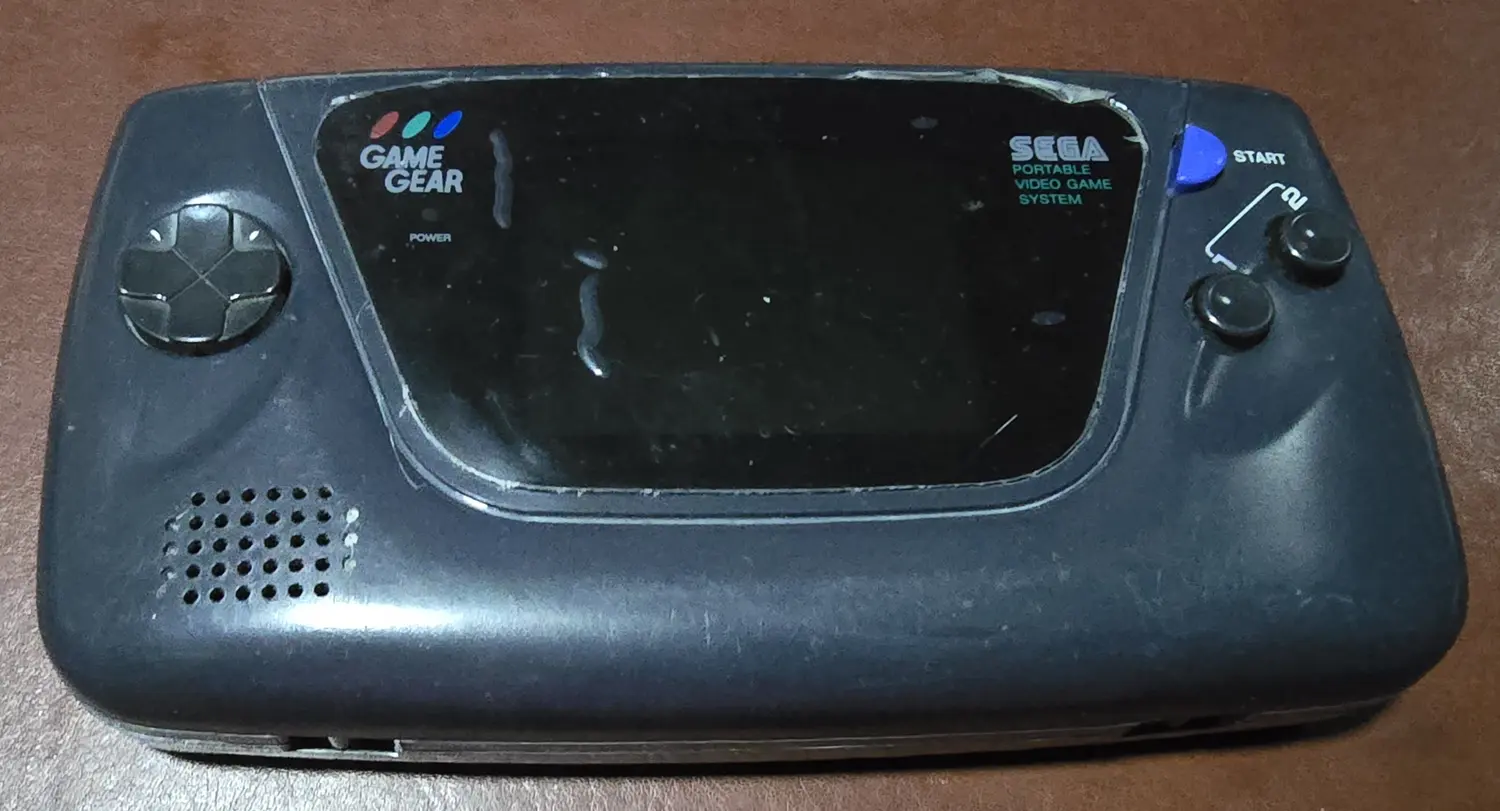 Front of the IPS-modded Sega Game Gear included in this listing, powered off, with the factory protective film still fitted over the screen lens