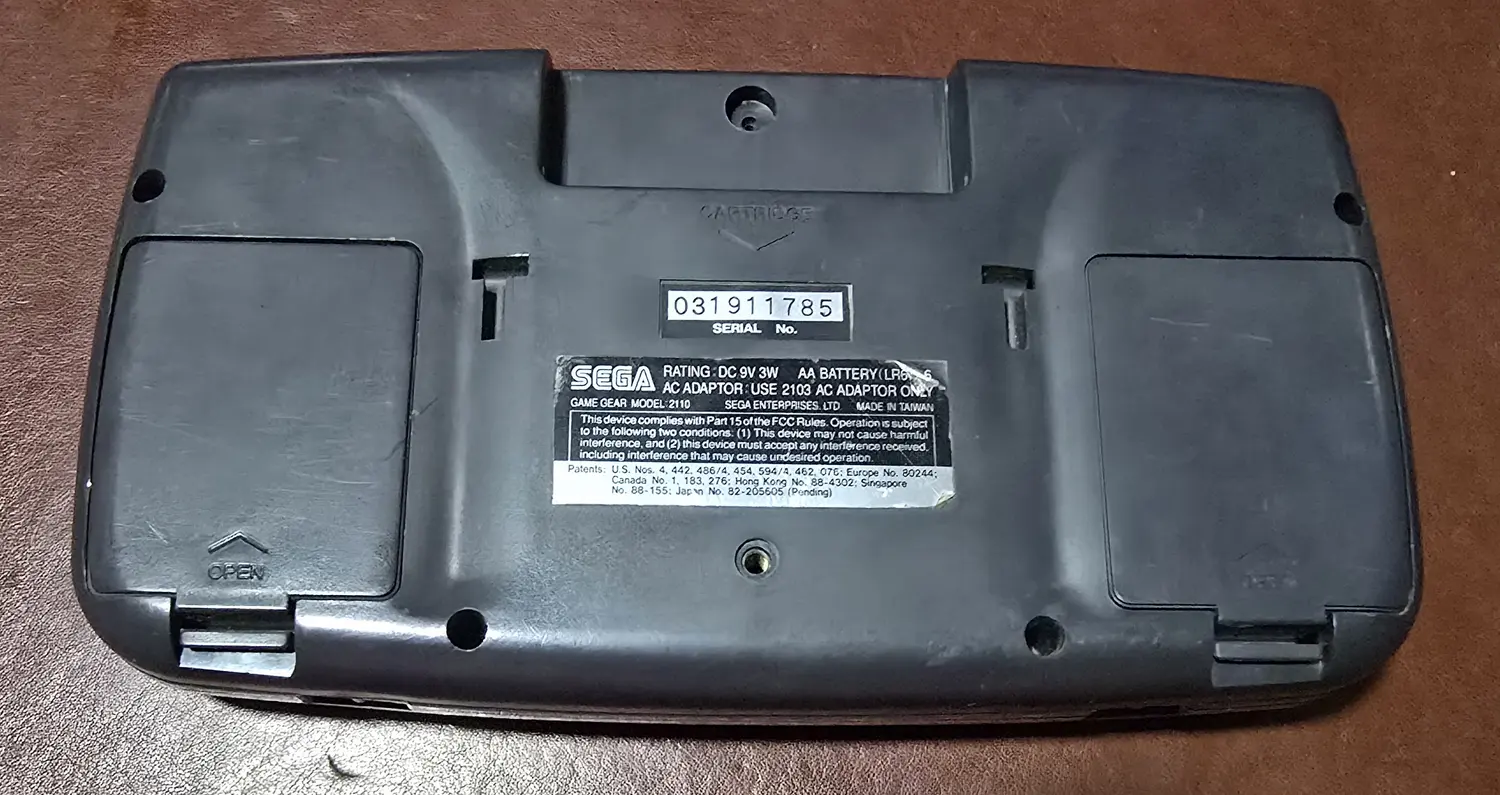 Back of the Game Gear with both original battery doors fitted, serial number 031911785 legible on the label