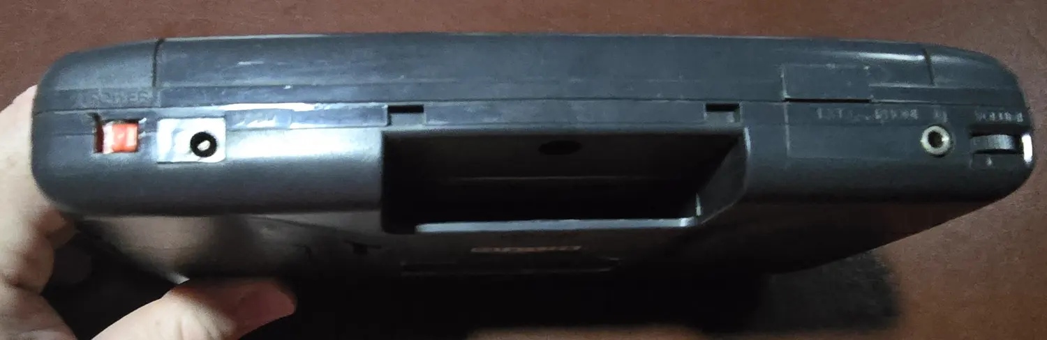 Top edge of the Game Gear showing the power switch, DC power jack, and empty cartridge slot