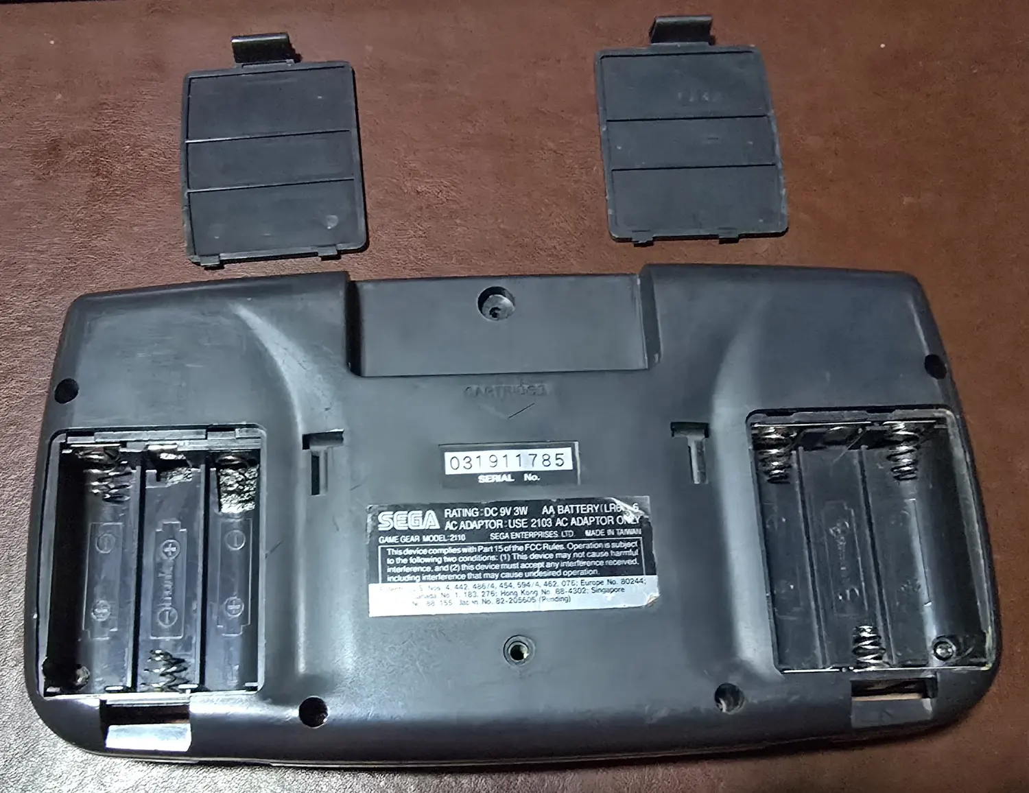 Both battery bays with the original doors removed, showing clean, uncorroded contacts and springs