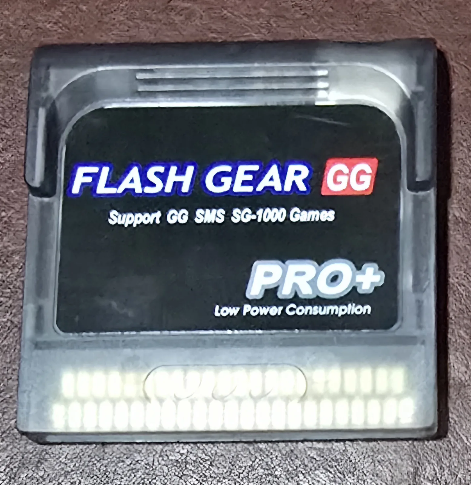 Front of the Flash Gear GG Pro+ flash cartridge in a semi-transparent smoky shell, label reading Support GG SMS SG-1000 Games