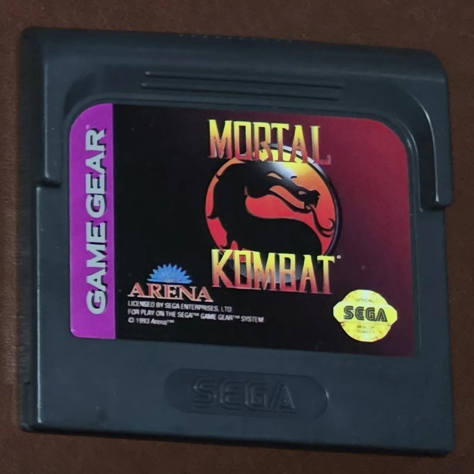 Front of an authentic Sega Game Gear Mortal Kombat cartridge, the black-and-purple dragon-logo label