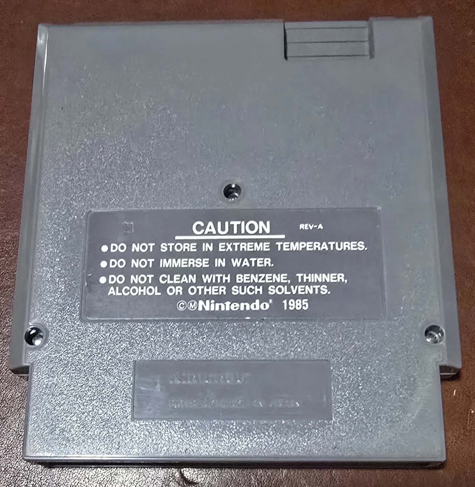 Back of the Dr. Mario NES cartridge shell with the REV-A caution label and the Nintendo 1985 molding