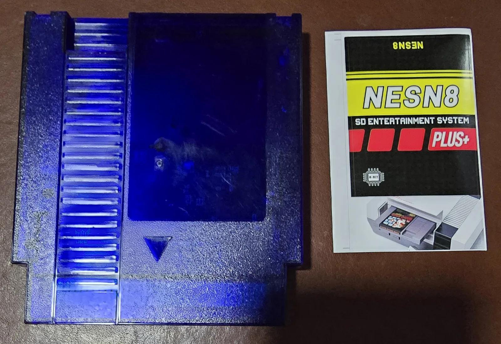The same flash cart board in a translucent blue NES shell alongside its instruction insert