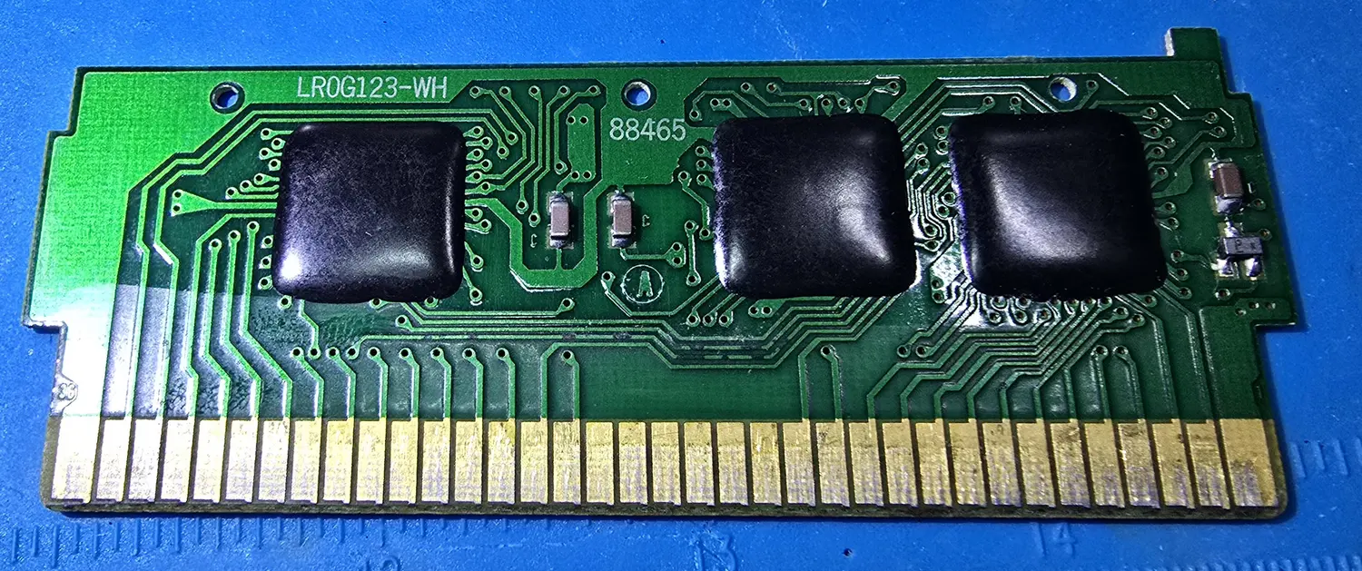 Component side of the World Class Track Meet 3-in-1 circuit board, three chips sealed under black epoxy blobs, silkscreen LR0G123-WH