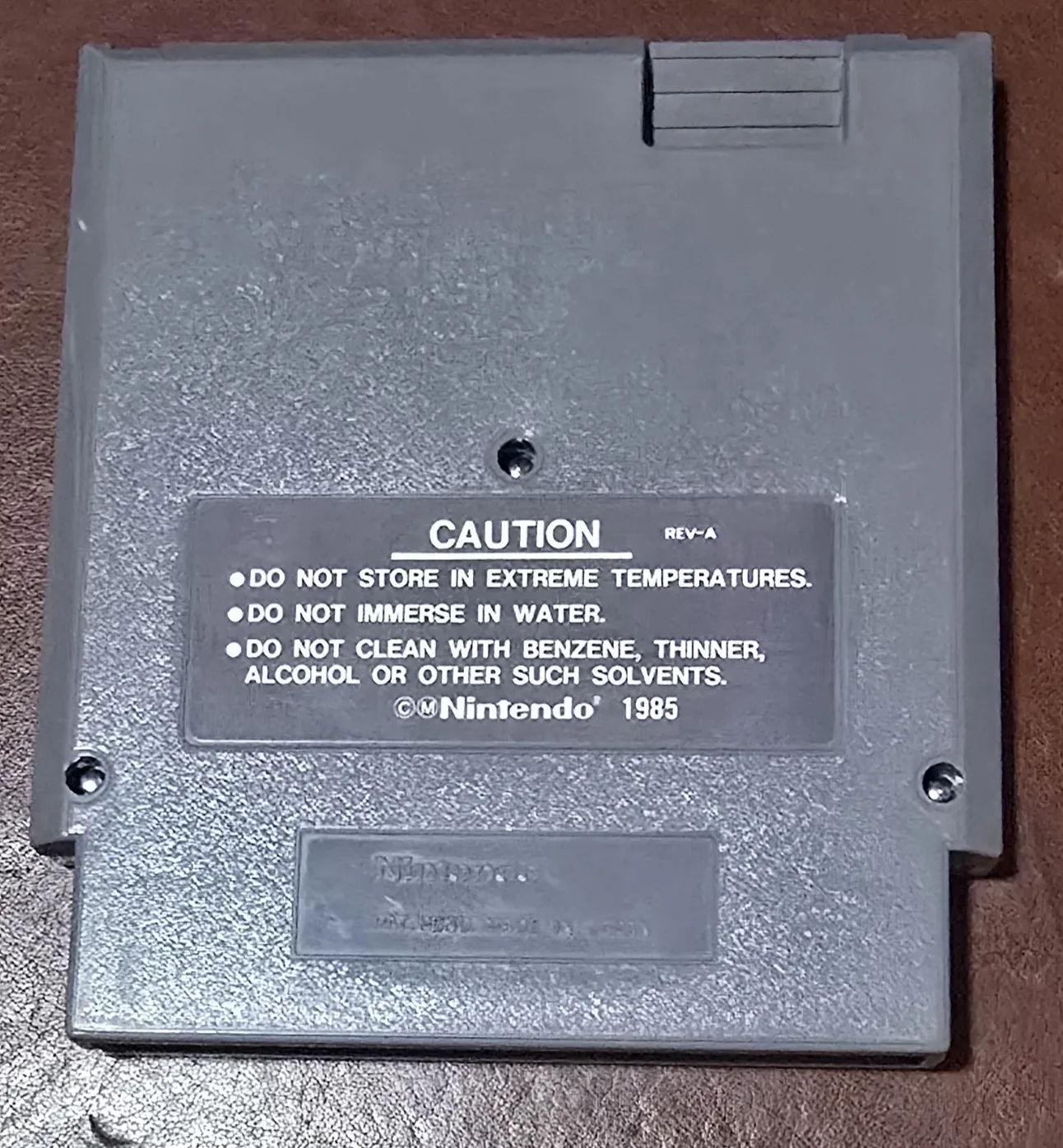 Back of the Super Mario Bros. slash Duck Hunt NES cartridge shell, REV-A caution label, Nintendo 1985