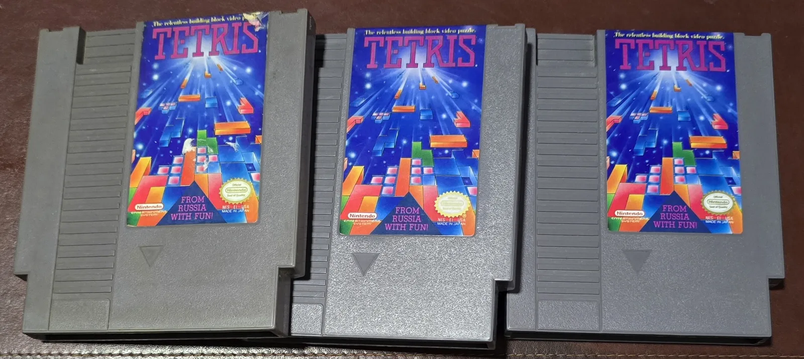 Three authentic NES Tetris cartridges fanned out, showing typical acceptable-or-better cosmetic condition