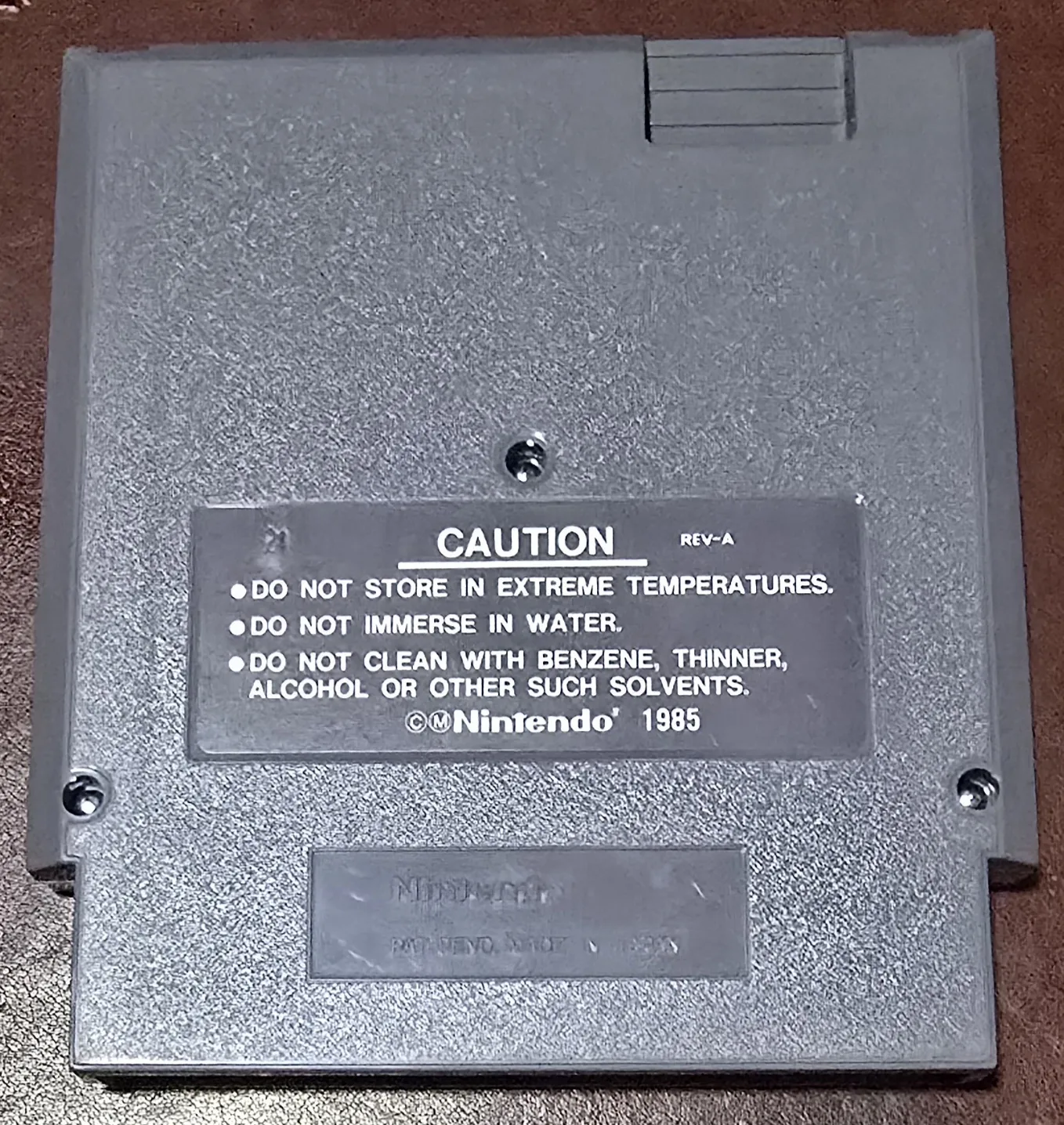 Back of the Tetris cartridge shell with the REV-A caution label and the Nintendo 1985 molding