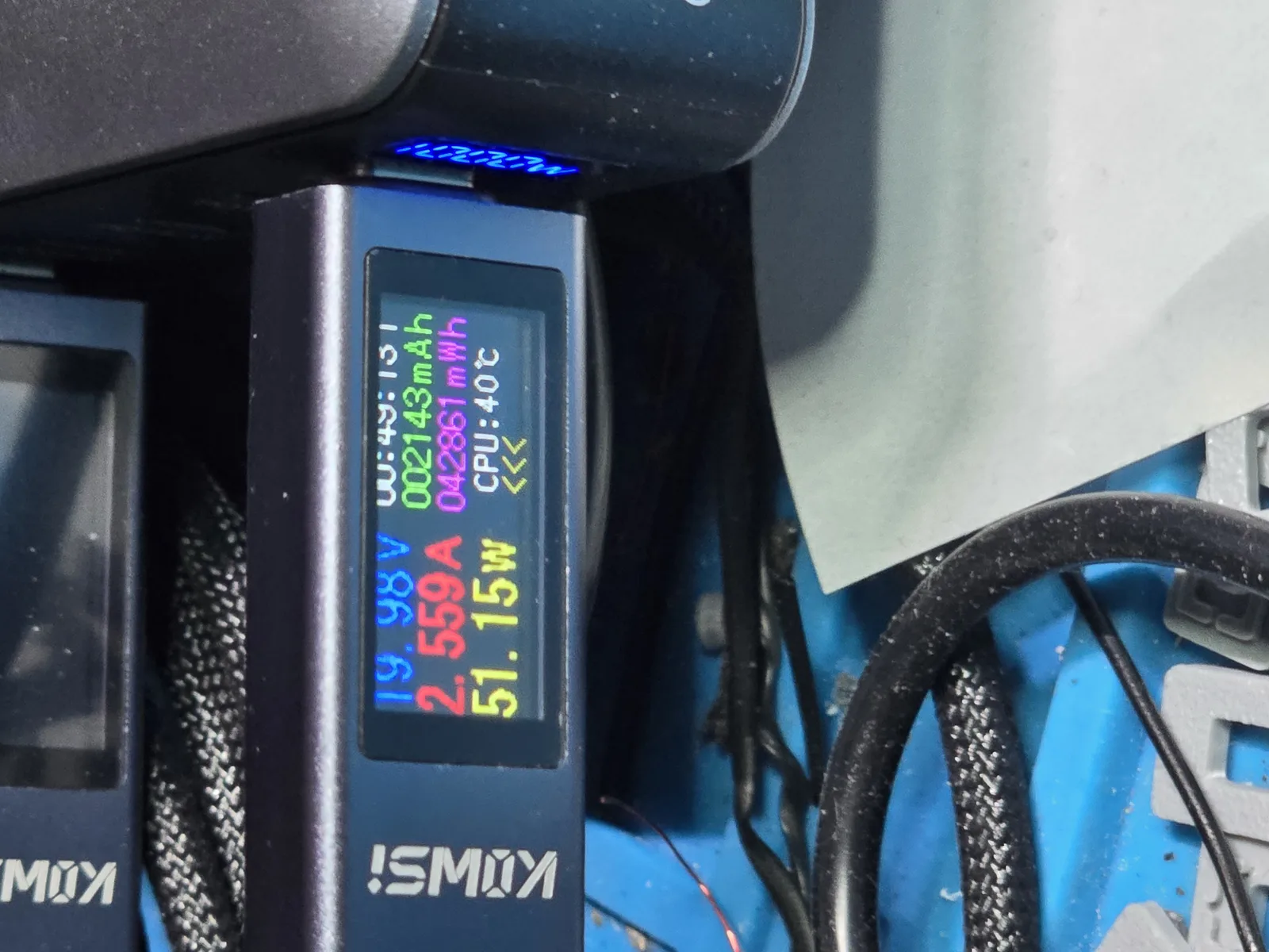 USB power meter showing 19.98 volts, 2.559 amps, 51.15 watts, with an elapsed timer reading 49 minutes and 13 seconds