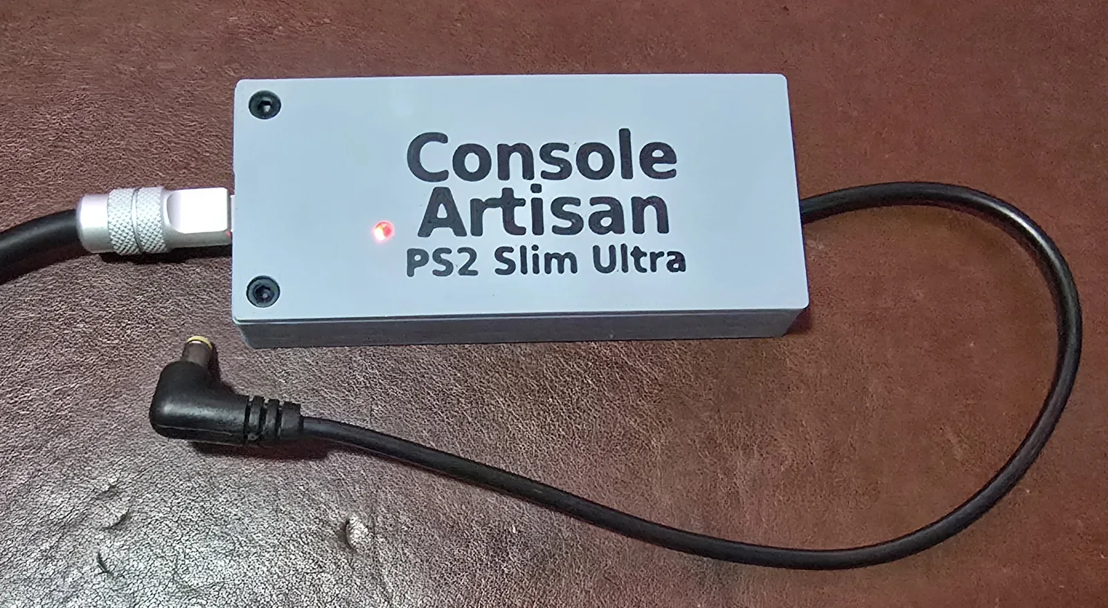 The front of the power supply with a USB-C cable plugged into one end and the small status LED on the lid lit red