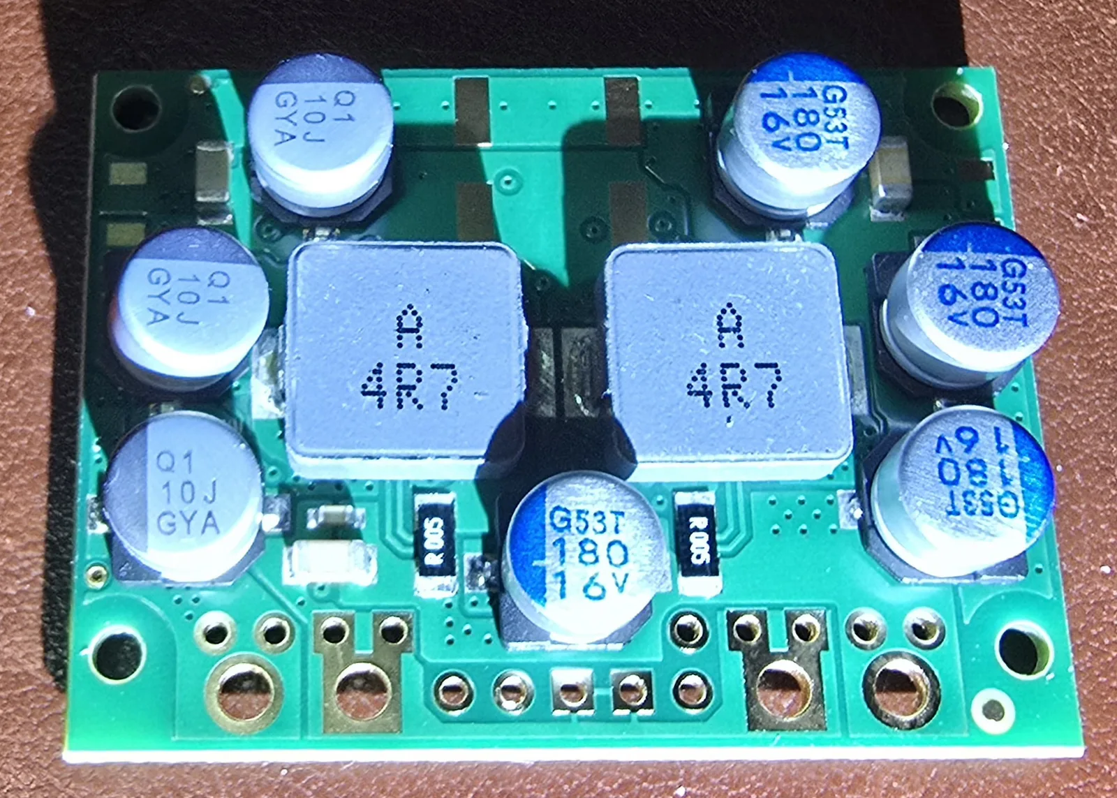 Close-up of the Pololu D42V110F8 buck converter board, showing two large shielded inductors marked 4R7 and six electrolytic capacitors