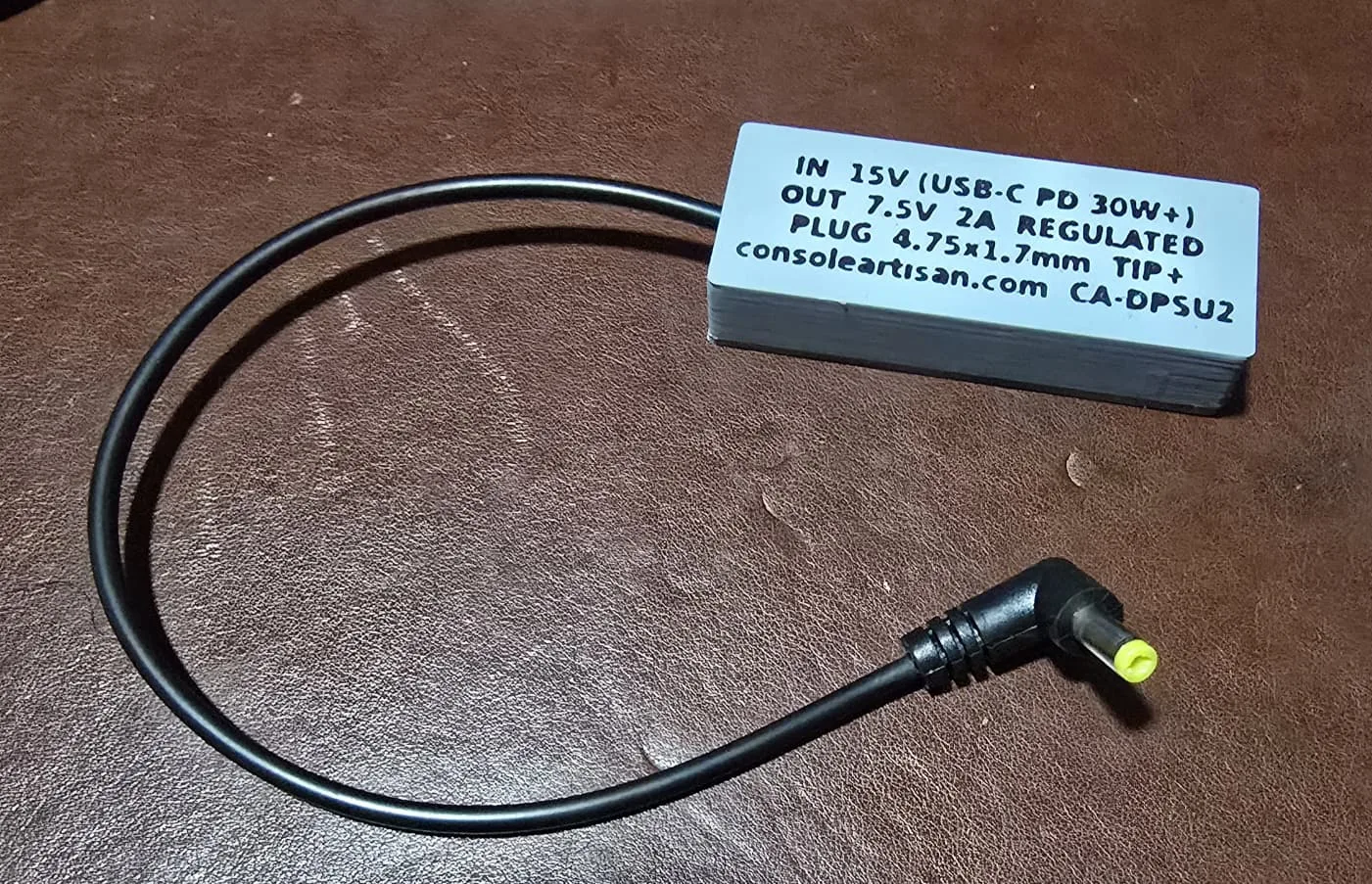 The back label of the adapter reading IN 15V USB-C PD 30W plus, OUT 7.5V 2A regulated, plug 4.75 x 1.7mm tip positive, consoleartisan.com, CA-DPSU2