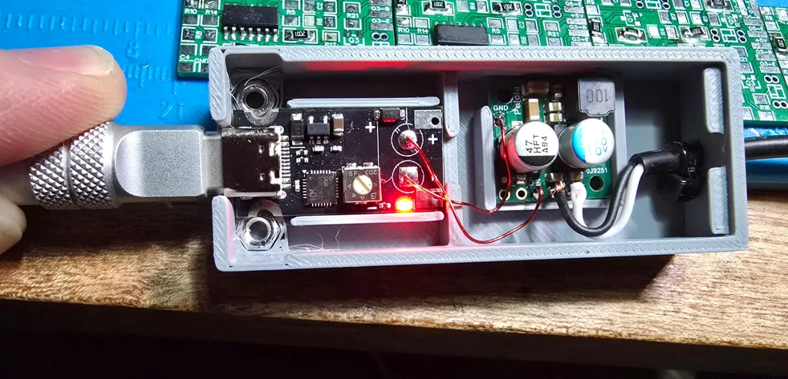 The adapter with its lid removed and powered up, showing both circuit boards in their separate bays and the trigger board's LED lit