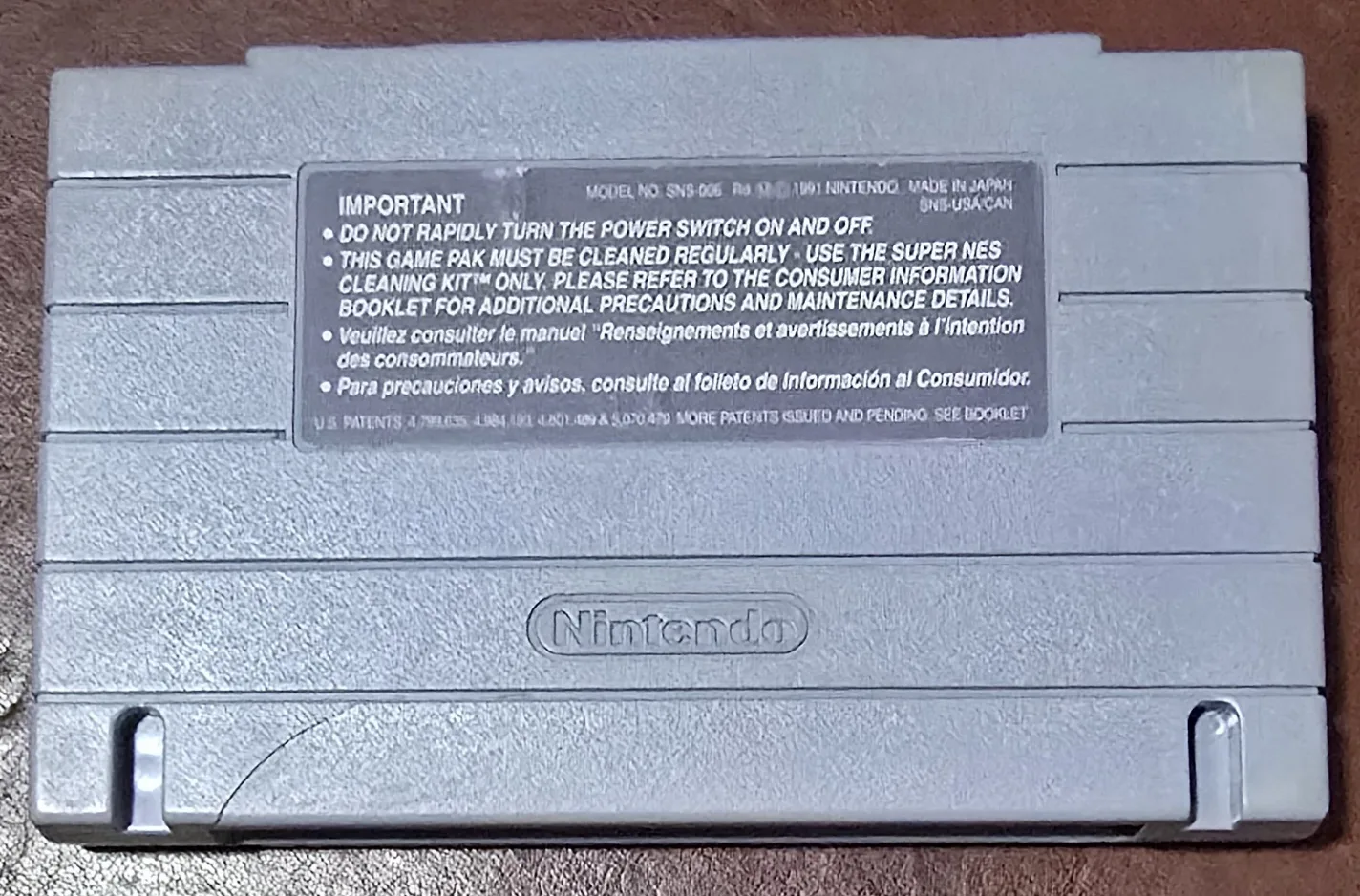 Back of the SNES Clue cartridge shell showing the Nintendo caution label and the 1991 molding