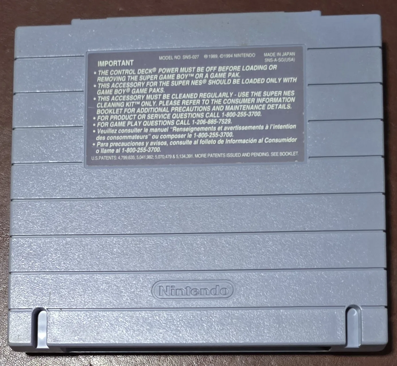Back of the Super Game Boy shell showing model number SNS-027, the US version, made in Japan, with the Nintendo caution label
