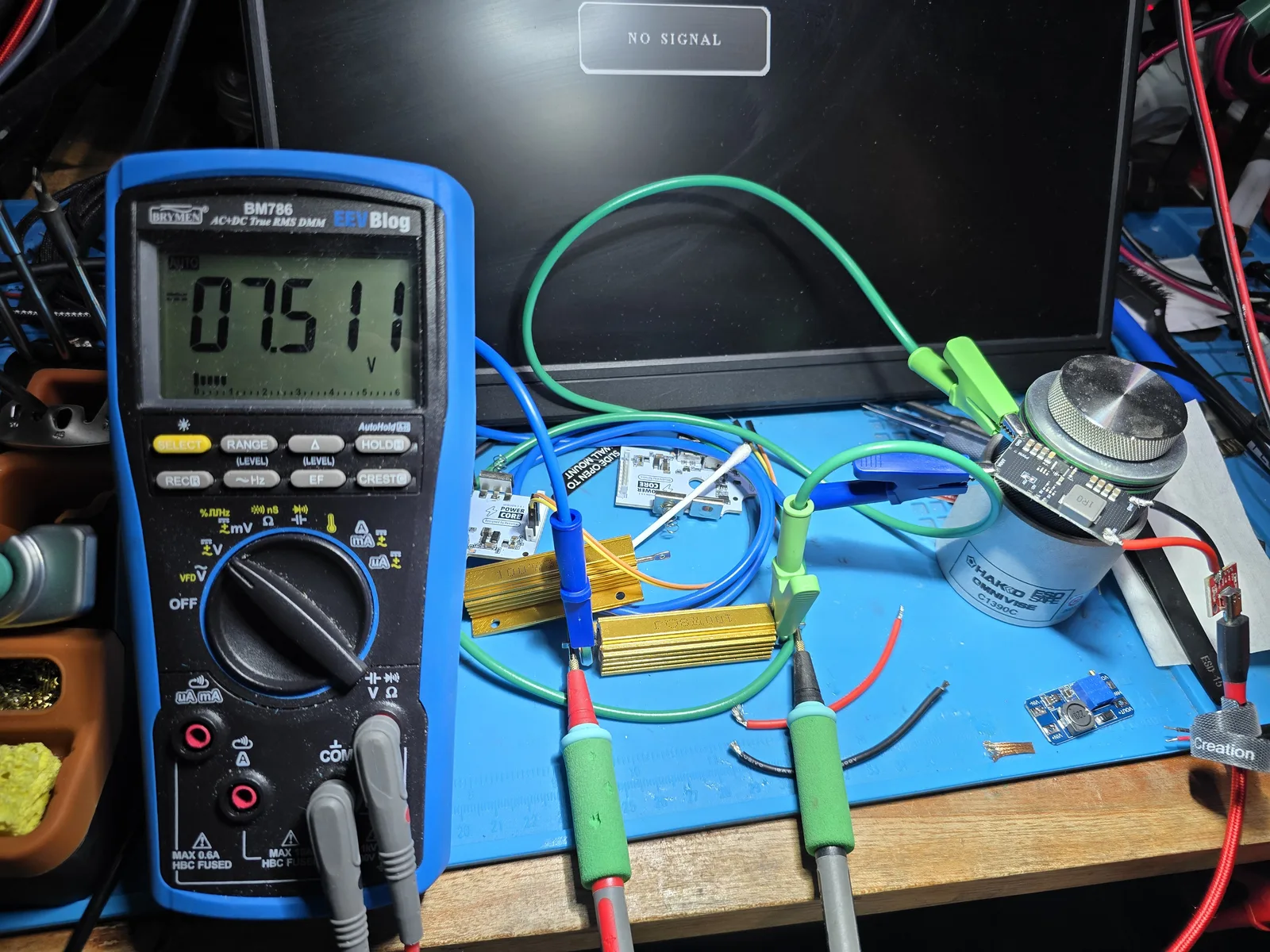 A multimeter confirming the adapter holds its regulated output voltage under a heavy power-resistor load