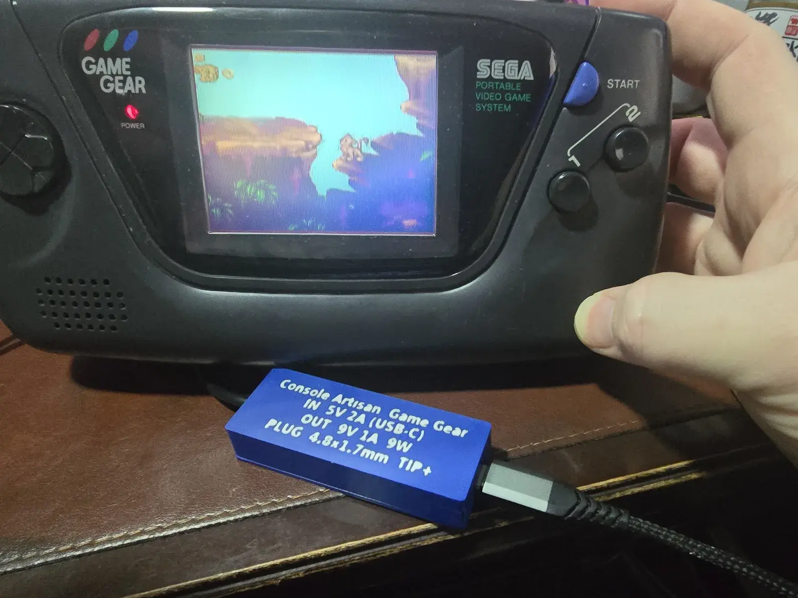 A Sega Game Gear running Sonic, powered by the Game Gear adapter