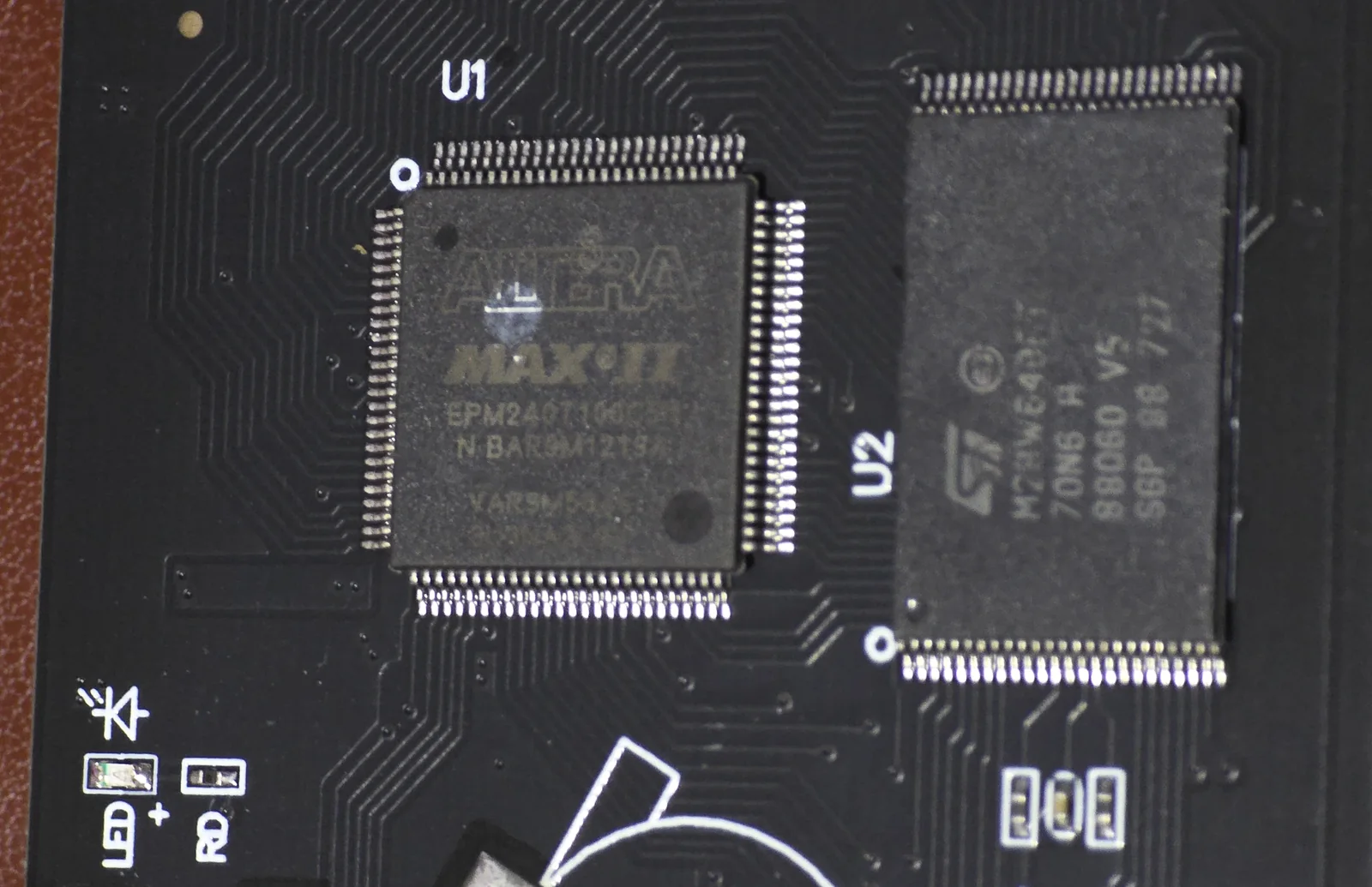 Close-up showing an Altera MAX II EPM240T100C5N CPLD at U1 and an ST M29W640 flash chip at U2 on the Mega EverGenesis board.